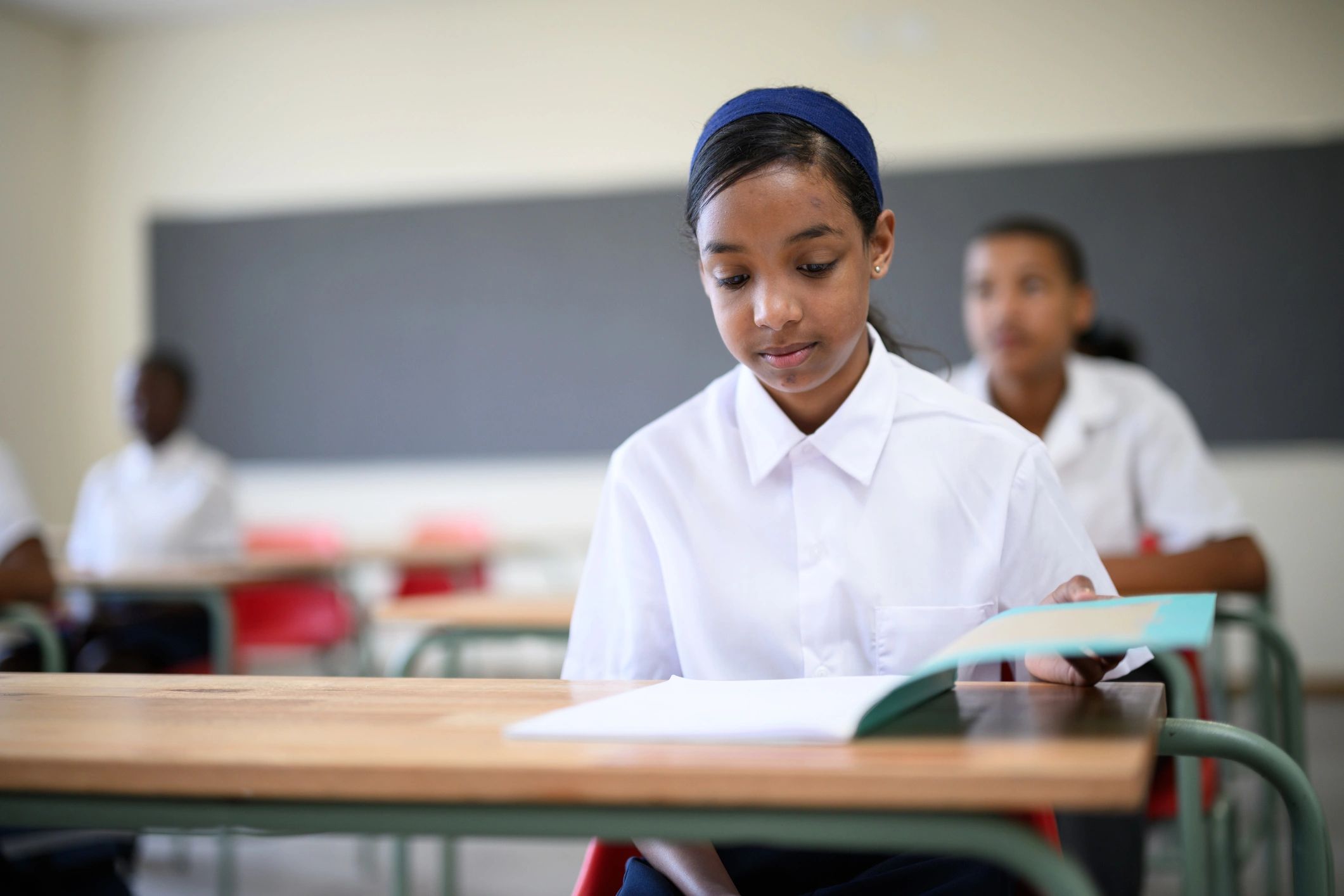 Schoolgirl learning with an open book in class